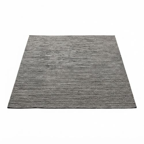 Grey handwoven cotton area rug beside a reading chair